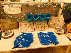 a table topped with paper cutouts and blue cups on top of each other next to wooden signs