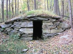 a stone structure with a door in the woods