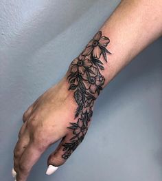 a woman's hand with black ink flowers on the left side of her arm