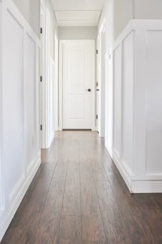 an empty hallway with white walls and wood floors