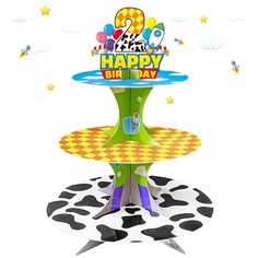 a happy birthday cake stand on top of a cow print tablecloth with balloons and stars