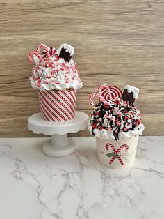 two cupcakes decorated with candy canes and marshmallows