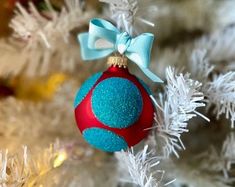 a blue and red ornament hanging from a christmas tree