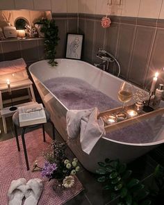 a bathtub with candles and towels on the floor next to it in a bathroom