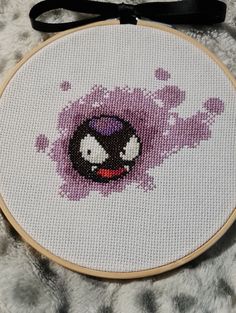 a cross stitch pattern with an angry bird on it's face and purple paint splattered in the background