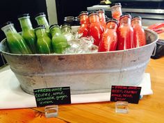 there are many different types of drinks in the buckets on this table, including green and red juice