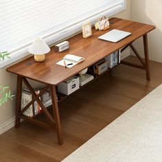 a wooden table with books and a laptop on it in front of a white window