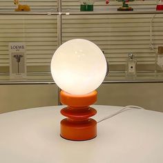 an orange table lamp sitting on top of a white table