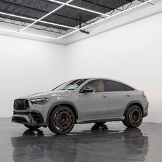 a grey mercedes suv parked in a white room with black and orange rims on the wheels