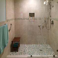 a walk in shower sitting next to a toilet and a wooden bench on top of a tiled floor