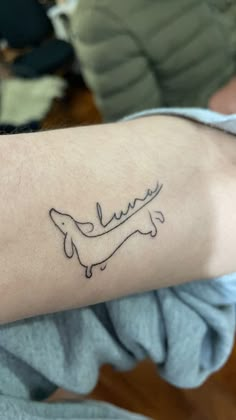 a person with a tattoo on their arm that has a dachshund drawn on it