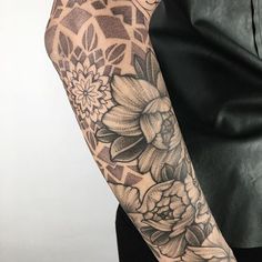 a woman's arm with flowers on it and an intricate pattern in the background