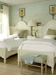 two white beds sitting next to each other in a bedroom