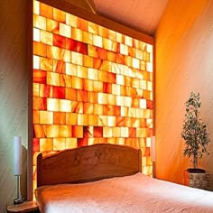 a bed sitting under a window next to a wooden headboard and night stand with a lamp on top of it