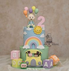 a birthday cake with an animal on top and rainbow decorations around the bottom tiers