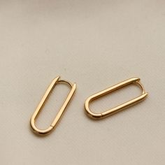 two gold paper clips sitting on top of a white surface with one open and one closed