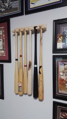 several baseball bats are hanging on the wall next to some framed photos and pictures,