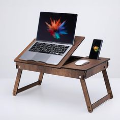 an open laptop computer sitting on top of a wooden desk next to a cell phone