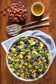 a salad with blueberries, corn and dressing in a bowl on a wooden table