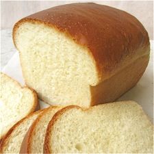 a loaf of white bread sitting on top of a table next to slices of bread