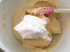 a white bowl filled with whipped cream next to a wooden spoon