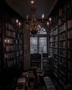 a chandelier hanging from the ceiling in a library filled with books