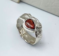 Sterling silver ring, with garnet pyrope, natural, and blood-red color, carved in a faceted teardrop (or pear-shaped) in 9 x 7 mm (0.35 x 0.28 inches). It has an irregular profile, obtained by melting the silver band in fire, which, due to the heat, acquires the final wrinkled shape. Unisex ring, of striking appearance that does not leave indifferent and ideal as a gift for men or women. Very light and comfortable to wear, you can use it daily for its comfort, or on special occasions for its ori Fine Jewelry Garnet Rings With Polished Finish, Garnet Rings In Fine Jewelry Style, Garnet Rings With Polished Finish - Fine Jewelry, Garnet Rings With Polished Finish, Garnet Gemstone Open Ring, Garnet Birthstone Open Ring, Modern Garnet Rings For Anniversary, Unique Garnet Gemstone Rings, Modern Garnet Ring Jewelry