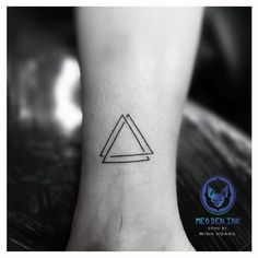 a black and white photo of a foot with a triangle tattoo on the left ankle