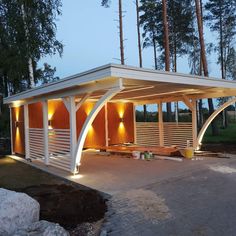 an outdoor pavilion lit up at night with lights on the roof and side doors open