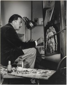 a man sitting in front of an easel painting