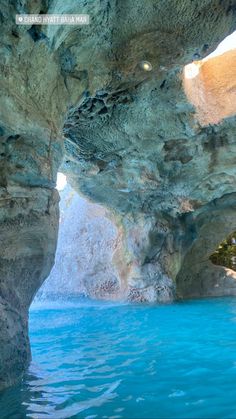 the inside of a cave with blue water and rock formations on it's sides