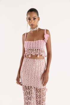 a woman wearing a pink crochet top and skirt with two pieces on the bottom