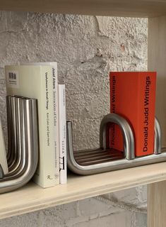 two books are sitting on a shelf next to some metal bookends and one has an orange book