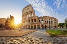 the roman colossion in rome, italy at sunset with sun shining through clouds