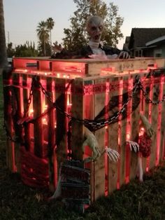 an old man sitting on top of a wooden crate covered in fake skeletons and chains