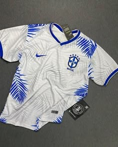 a soccer jersey with blue and white designs on it, sitting on a gray surface