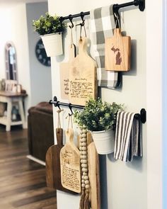 kitchen utensils hanging on the wall with potted plants and wooden cutting boards