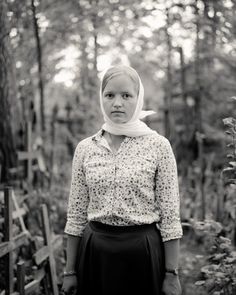 a woman standing in the woods wearing a hijab and looking at the camera