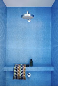 a blue tiled bathroom with a towel on the shelf