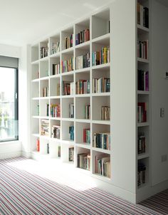 a large white book shelf filled with lots of books on top of a carpeted floor