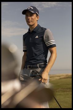 a man standing on top of a lush green field holding a golf racquet