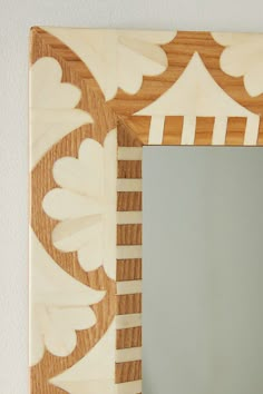 a mirror that is sitting on top of a wooden frame with an intricate design in the middle