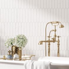 a bathtub with white flowers in it and a gold faucet next to it