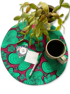 a cup of coffee sitting on top of a table next to a potted plant