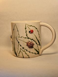 a coffee cup with two ladybugs on it sitting in front of a white background