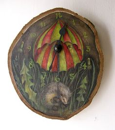 a clock with an umbrella painted on the side of it's face and two hedgehogs underneath it