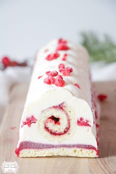 a cake with white frosting and red sprinkles on it sitting on top of a wooden table