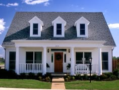 a white two story house with black shutters on the front door and porches