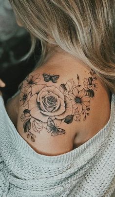 a woman's back shoulder tattoo with flowers and butterflies on her chest, which is covered in black ink