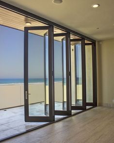 an empty room with sliding glass doors leading out to the beach and ocean in the distance